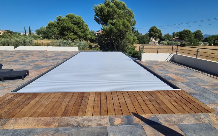 Volet immergé fermé sur une piscine à débordement à Éguilles, la fosse cachée sous un caillebotis bois