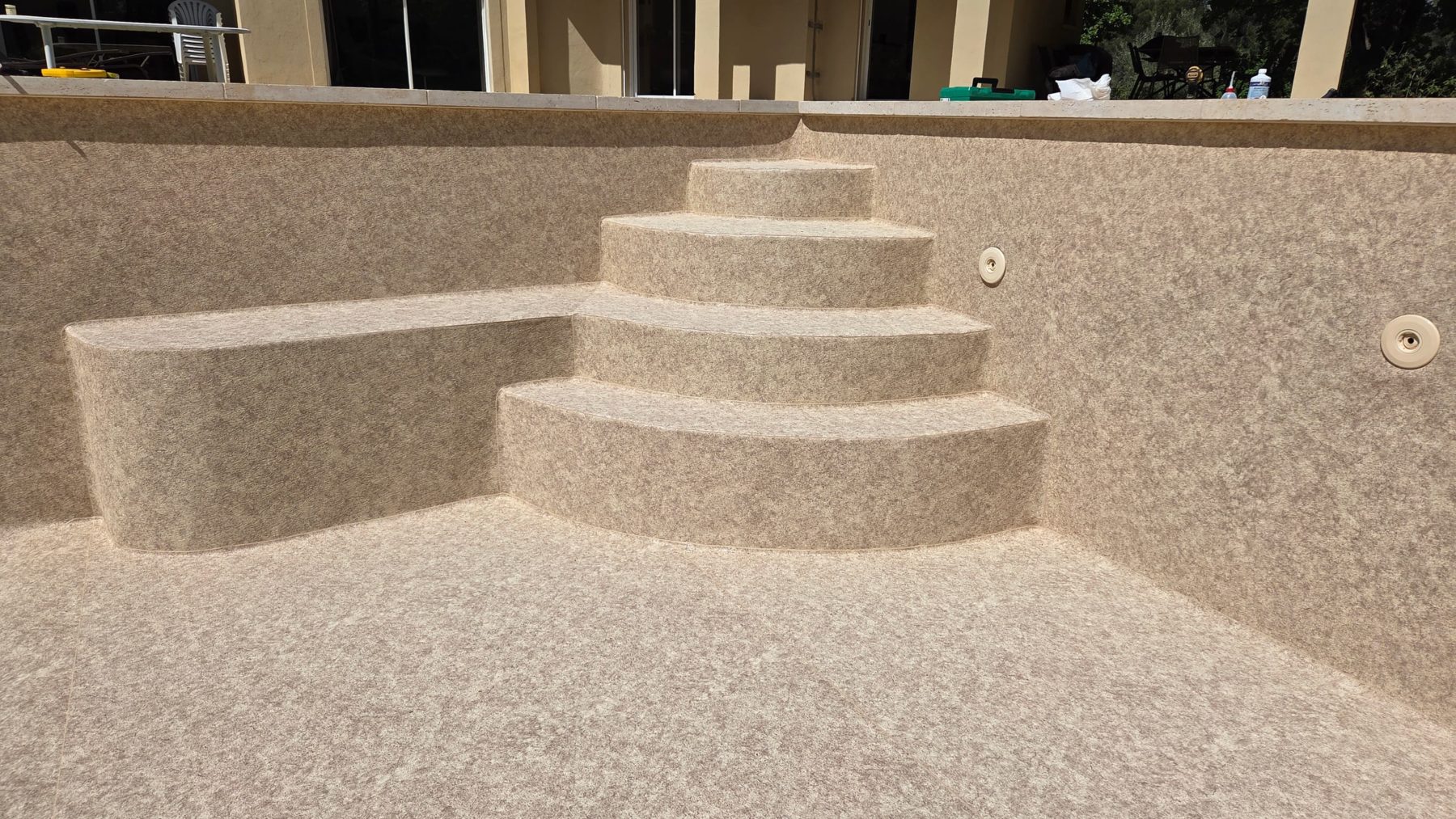 Escalier maçonné d’angle arrondi et banquette recouverts en PVC armé Aquasense Granit Sand (CGT Alkor)