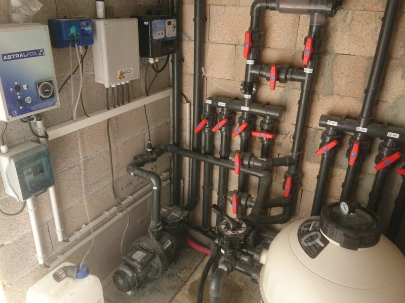 Nourrice de vannes, pompe et filtre dans un local technique de piscine